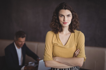 Portrait of beautiful woman standing with arms crossed in restaurantの写真素材
