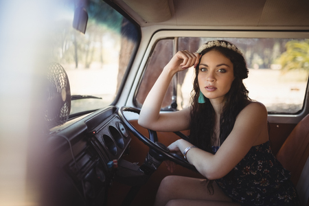 Portrait of beautiful woman leaning on steering wheel while sitting in vanの写真素材