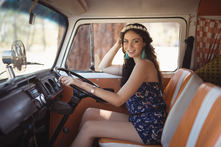 Portrait of smiling young woman sitting in motor home on sunny dayの写真素材