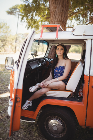 Portrait of young woman sitting in motor home on sunny dayの写真素材
