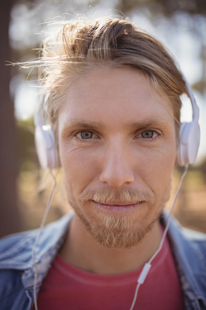 Close up portrait of man listening music on headphone while standing at fieldの写真素材