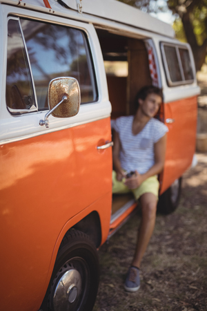 Young man sitting in van at forestの写真素材