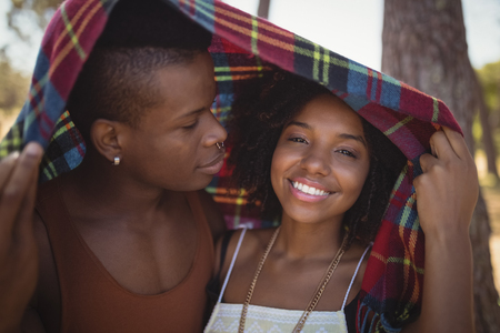 Close up of smiling couple in blanket at forestの写真素材
