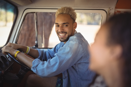 Cheerful man looking at woman while driving vanの写真素材