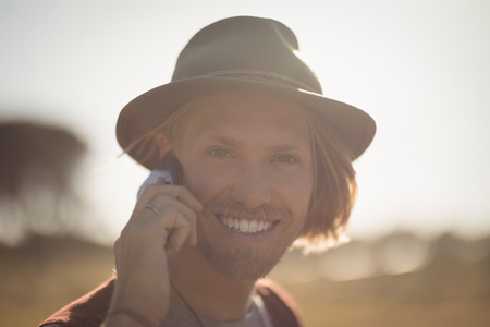 Portrait of smiling young man talking on phone against skyの写真素材