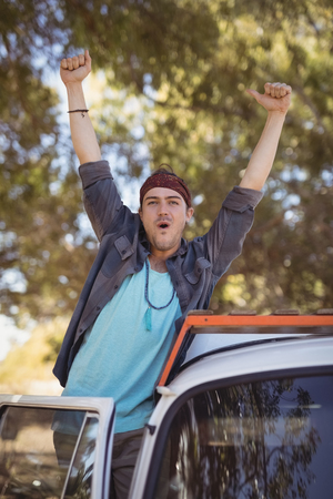 Portrait of young man with arms raised standing by van