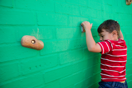 Rear view of boy climbing wall at playground in schoolの写真素材