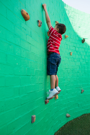 Side view of boy climbing wall at playground in schoolの写真素材