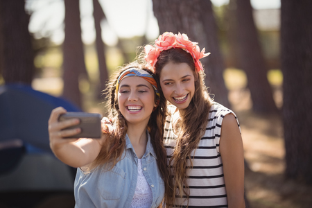 Happy female friends taking selfie together at forestの写真素材