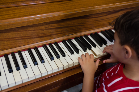 Close up of boy playing piano in classroom at schoolの写真素材