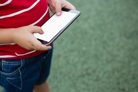 Cropped image of boy using smart phone while standing on grassy fieldの写真素材