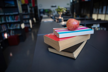 Apple on stack of books in liabrary at schoolの写真素材