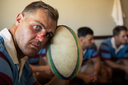 Portrait of wounded player sitting with team at locker roomの写真素材