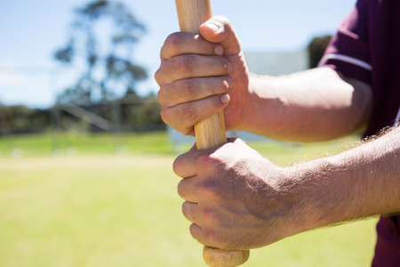 Cropped image of player holding baseball bat at playing field