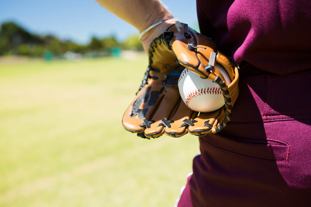 Mid section of baseball pitcher holding ball in glove on sunny dayの写真素材
