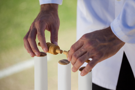 Cropped image of referee putting bails on cricket stumps during matchの写真素材