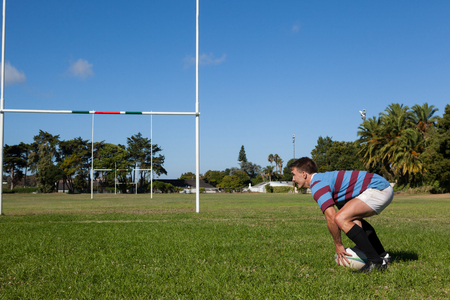 Side view of rugby player crouching on field during sunny dayの写真素材