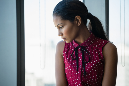 Thoughtful executive looking through window in officeの写真素材