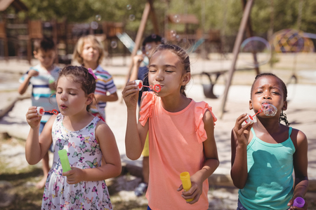 Schoolkids playing with bubble wand at school playgroundの写真素材