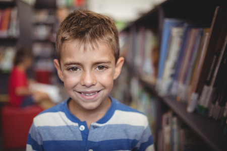 Portrait smiling schoolboy standing in library at schoolの写真素材