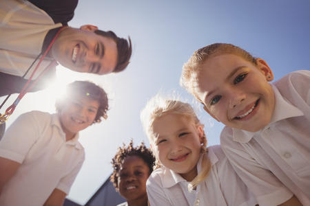 Portrait of smiling coach and schoolkids in schoolyardの写真素材