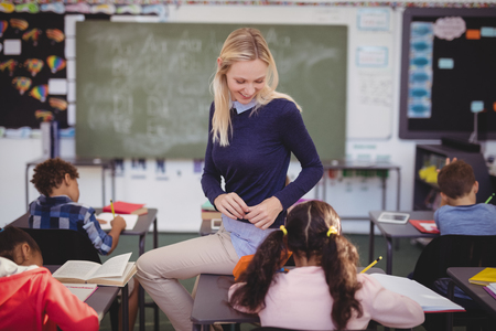 Teacher helping schoolkids with their homework in classroom at schoolの写真素材