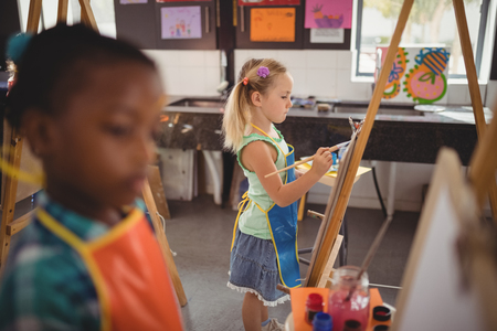 Attentive girl panting on canvas during drawing classの写真素材