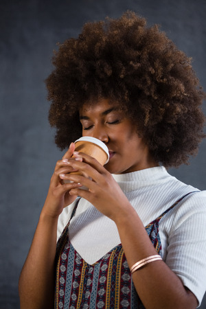 Close up of woman with closed eyes drinking coffee against wallの写真素材