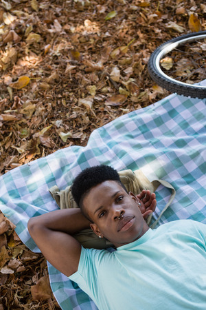 Portrait of young man relaxing on a picnic blanketの写真素材