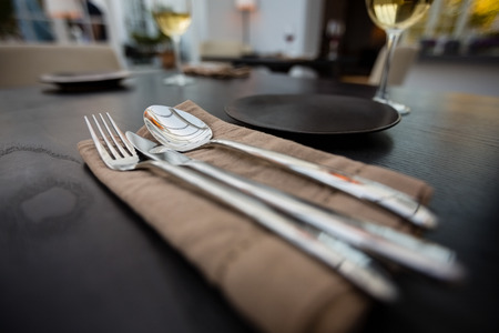 Close up of eating utensils and napkin on table at restaurantの写真素材