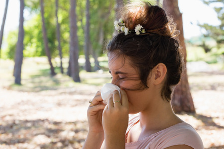 Woman suffering from cold and flu in the parkの写真素材