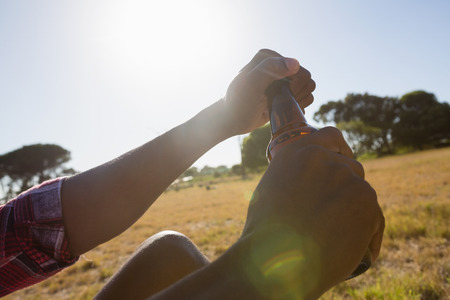 Man opening the lid of beer bottle on a sunny dayの写真素材