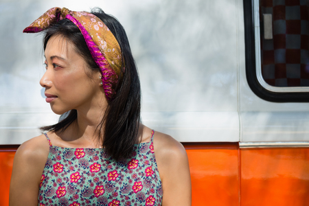 Thoughtful woman leaning on camper van in the parkの写真素材