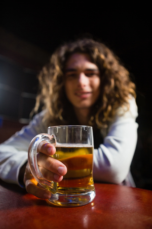 Young man holding beer mug in bar