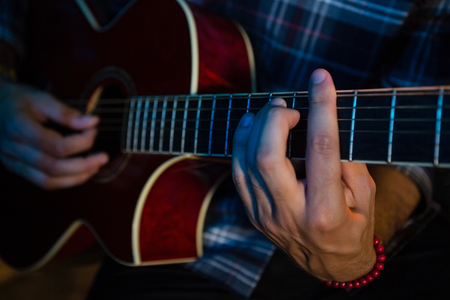 Mid section of musician playing guitar on stage in nightclubの写真素材
