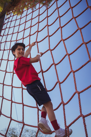 Boy climbing a net during obstacle course training in the boot campの写真素材