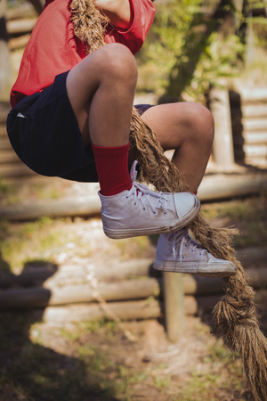 Kid climbing a rope during obstacle course training in the boot campの写真素材