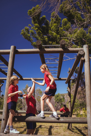 Trainer and girl giving high five to each other during obstacle course training in the boot campの写真素材