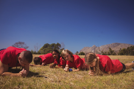 Trainer instructing kids while exercising in the boot camp on a sunny dayの写真素材