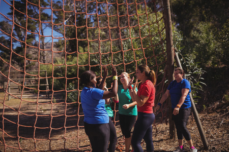 Group of fit women giving high five to each other in the boot camp on a sunny day
