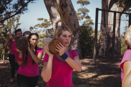 Group of women carrying a heavy wooden log during obstacle course in the boot campの写真素材