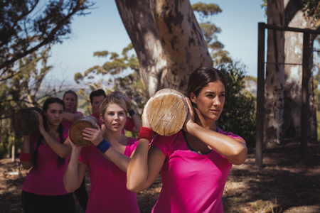 Group of women carrying a heavy wooden log during obstacle course in the boot campの写真素材