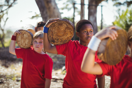 Kids carrying wooden log during obstacle course training in the boot campの写真素材