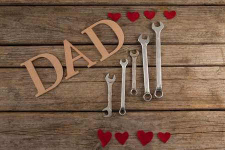 High angle view of dad text by wrenches and heart shapes on wooden tableの写真素材