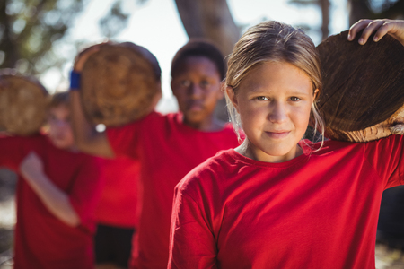 Kids carrying wooden log during obstacle course training in the boot campの写真素材