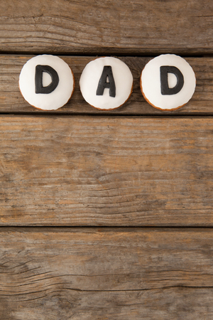 Overhead view of white cookies with black dad text on wooden tableの写真素材