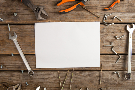 Overhead view of blank paper amidst hand tools on wooden tableの写真素材