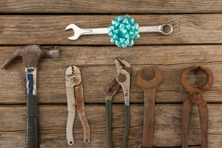 Overhead view of wrench with ribbon by hand tools on wooden tableの写真素材