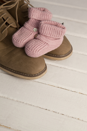 High angle view of baby booties with mans shoes on wooden floorの写真素材