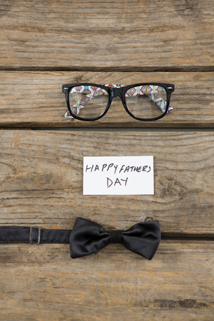 High angle view of happy fathers day text by eyeglasses and  bow tie on tableの写真素材